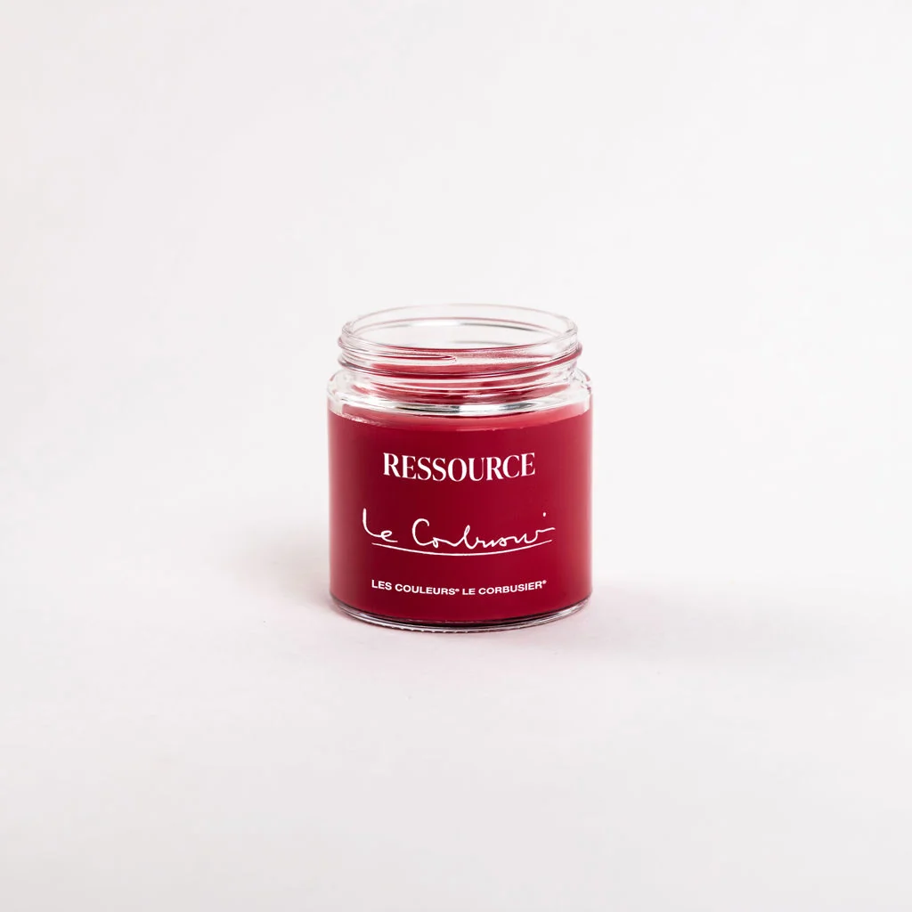 An open glass jar of red paint bearing the Ressource and Les Couleurs Le Corbusier names, photographed against a pale background.