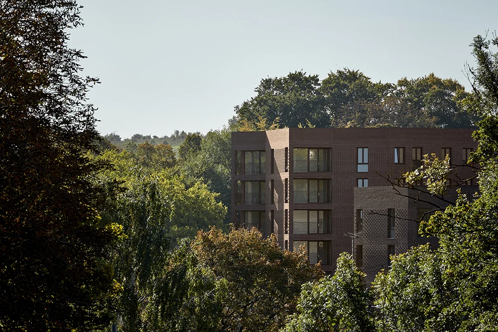 Brick apartment buildings at Lion Green Road framed by mature trees.